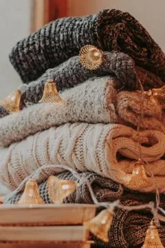 Home decor, sweaters, a stack of books and light bulbs, cozy winter interior  Stock Photos