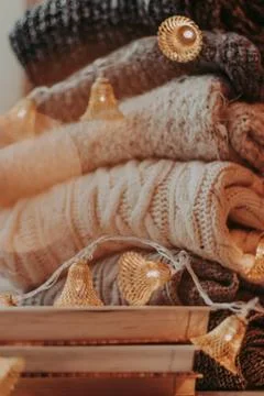Home decor, sweaters, a stack of books and light bulbs, cozy winter interior  Stock Photos