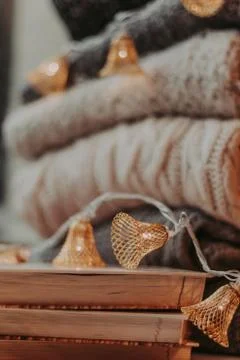 Home decor, sweaters, a stack of books and light bulbs, cozy winter interior  Stock Photos