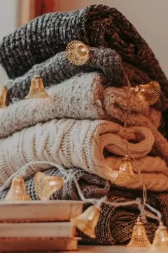 Home decor, sweaters, a stack of books and light bulbs, cozy winter interior  Stock Photos