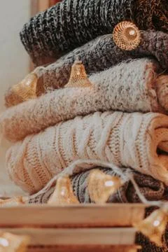 Home decor, sweaters, a stack of books and light bulbs, cozy winter interior  Stock Photos