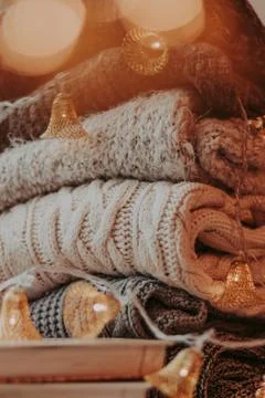Home decor, sweaters, a stack of books and light bulbs, cozy winter interior  Stock Photos