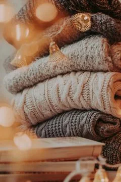 Home decor, sweaters, a stack of books and light bulbs, cozy winter interior  Stock-Fotos