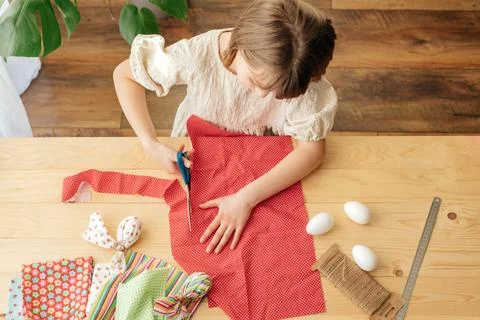 Home decoration for Easter. Top view of a girl who makes eggs from a fabric in Stock Photos