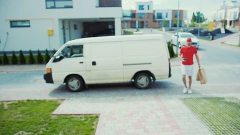 Home delivery services. Young cheerful man corrier in uniform arriving at the Stock Footage 113791908