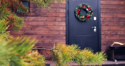 Home door in pine forest, adorned with Christmas wreath, evokes seasonal Stock Footage 256901746