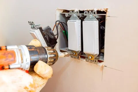 Home electrical upgrade in progress with careful modifications to wall switches Stock Photos