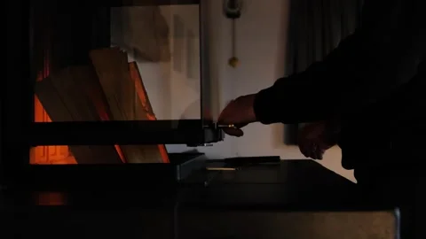 Home fireplace.man closes a burning fireplace in a dark room. Cozy atmosphere. Stock Footage 246979965