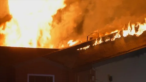 Home fully engulfed in flames with fire shooting through the roof Stock Footage 110705126