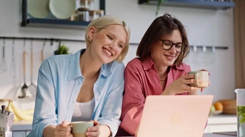 Home girlfriends talking computer looking screen at calm kitchen morning closeup Stock Footage 335104206