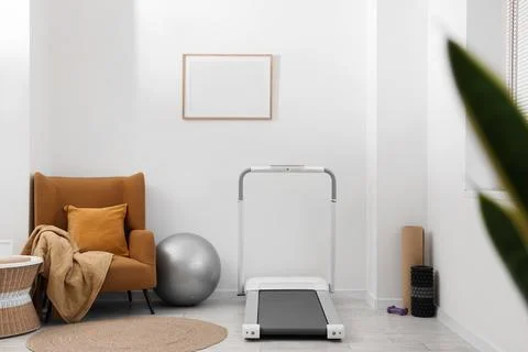 Home gym setup with treadmill, exercise ball, and armchair in a modern minima Stock Photos
