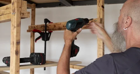 Home improvement, man assembling wood shelf at home screwing wood slats Stock Footage 321879573