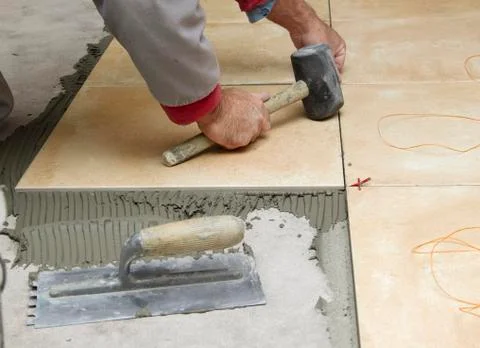 Home improvement, renovation - handyman laying tile with level Stock Photos