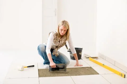 Home improvement, renovation - handywoman laying tile Stock Photos