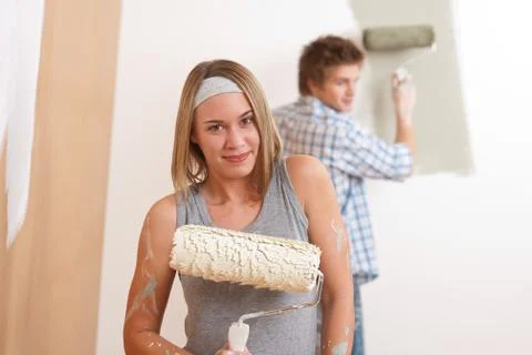 Home improvement: young man and woman painting wall Stock Photos