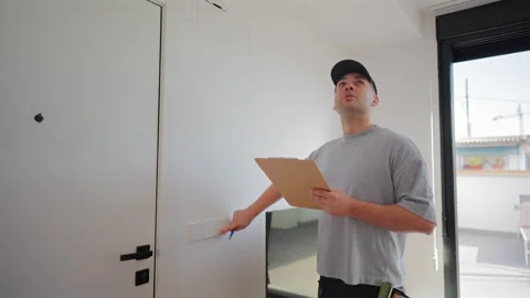 Home inspector checking light switch and making notes on clipboard for. Видео 342908276