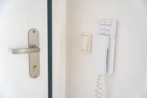Home intercom system mounted beside an apartment entrance door. Residential Stock Photos