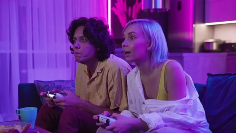 Home isolated couple push and shove each other as they play a video game at home Stock Footage 145375643
