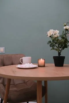 Home kitchen interior - cup of tea, plate with marshmellow, burning candle Stock Photos