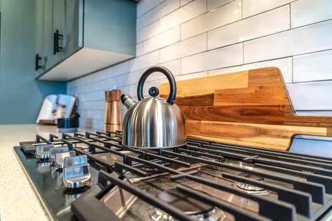 Home kitchen interior with kettle over the burner of a cooktop with five knobs Stockfoto's