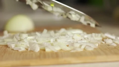 At home in the kitchen, a man slices a white onion with a metal knife on a Stock Footage 249282673