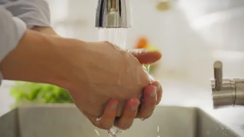 In the home kitchen young man washes his hands under the tap. He carefully w Stock Footage 281091178