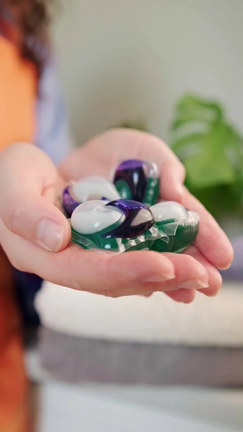 Home laundry with washing capsules, combining detergent, softener, and bleach in Stock Footage 295286182