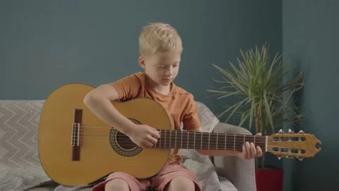 Home Lesson Boy Kid Playing The Guitar. boy in white hat plays guitar at home. c Stock Footage 158856045