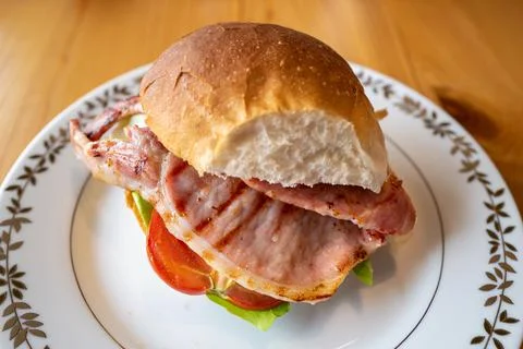 Home made bacon, lettuce and tomato burger on a white plate Stock Photos