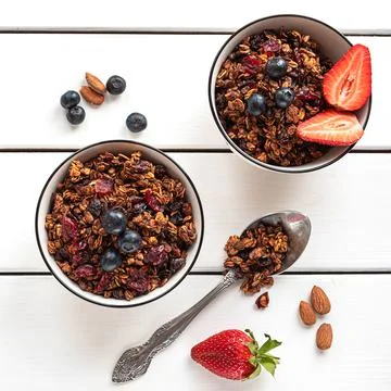 Home-made baked granola in two bowls, with berries and almonds Stock Photos