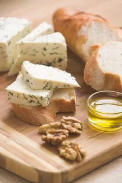 Home made cheese and walnuts, olive oil and bread on a wooden board.  Stock Photos