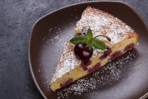 Home made cherry pie with icing sugar and mint over black rustic background Stock Photos