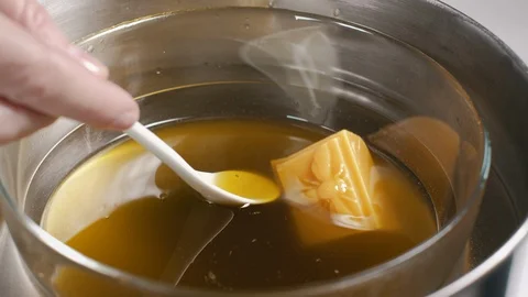 Home made ointment creating process. Adding bees wax  into herbal oil base. 4K Stock Footage 127714374