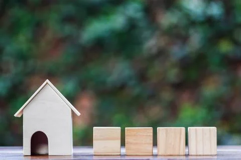 Home model and four empty wooden square block or cube on wood table. Stock Photos