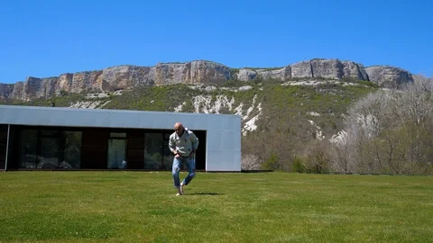 At home in the mountains. A Middle-aged man doing workout on the grass Stock Footage 129559822