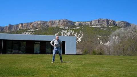 At home in the mountains. A Middle-aged man doing workout on the grass. Jumping Stock Footage 129559840