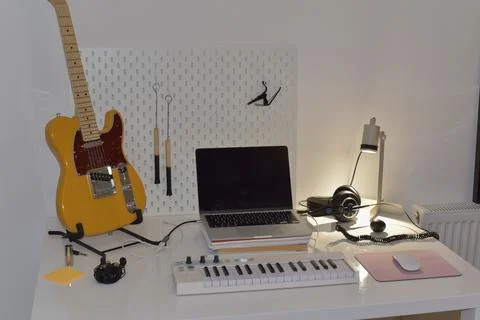 Home music studio setup featuring electric guitar, laptop, and MIDI keyboard Stock Photos