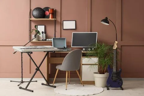 Home music studio setup with keyboard, electric guitar, computer monitor, and Stock Photos