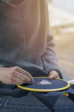 Home needlework concept, ross-stitched pillow in female hands. Stock Photos