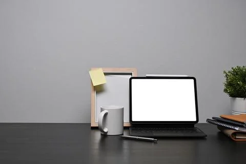 Home office desk with computer tablet, picture frame and coffee cup on black Stock Photos
