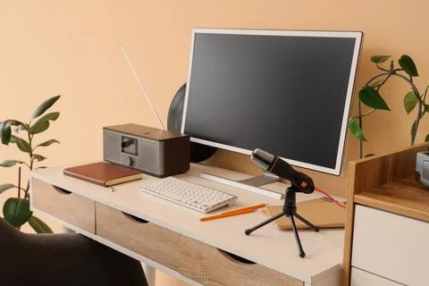 Home office desk setup with computer monitor, microphone, radio, and keyboard Stock Photos