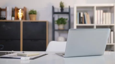 Home office interior with laptop computer and paperwork on white table. Stock Photos