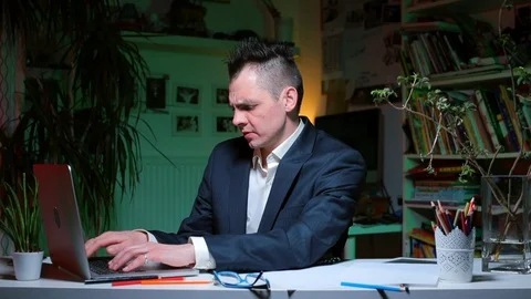 Home office in isolation. A man does work sitting at a table at a computer. Stock Footage 128027968