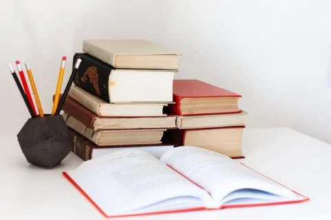 Home office: open textbook, notebook, stack of old books retro education back Stock Photos