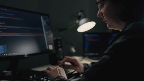 Home office, a programmer sits at a desk cluttered with computer equipment. Stock Footage 241728181