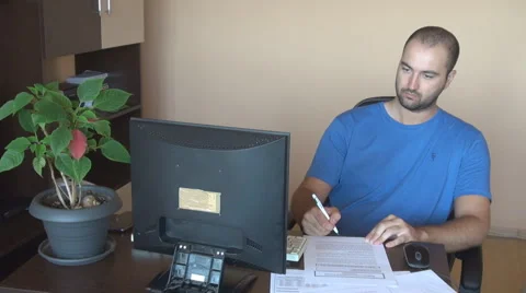 Home office, young man with working papers on desk writing, checking computer Stock Footage 40109256