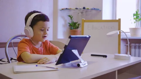 Home online learning. A boy in white headphones watches an online lesson Stock Footage 171416662