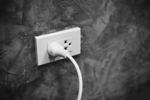 Home outlet plug is plugging socket on wall with white power cord cable - Pow Stock Photos