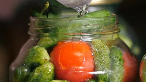 Home preservation. Assorted tomatoes with cucumbers in glass jars are poured Stock Footage 315245772