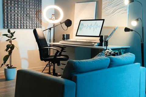 Home recording studio setup with laptop displaying audio waveform, ring light Stock Photos